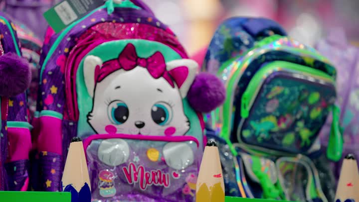 مفهوم التسوق للأبناء، تصوير مقرب لامرأة عربية خليجيه اماراتية محجبة ترتدي العباءة داخل متجر تقوم باختيار حقيبة مدرسية ملونة للأطفال، الاستعداد للمدرسة و المستلزمات المدرسية، اختيار المنتجات المناسبة للأطفال، العناية بالأسرة