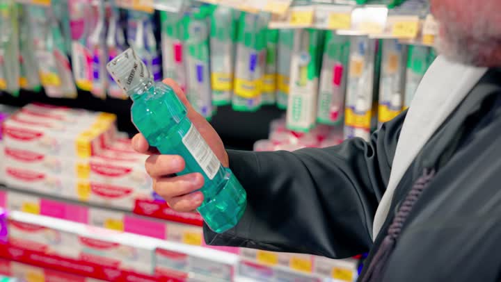 العناية الشخصية والنظافة، تصوير مقرب ليد رجل عربي خليجي اماراتي يقف داخل سوبرماركت يمسك عبوة منتج عناية شخصية من على الرفوف، مفهوم التسوق اليومي، اختيار المنتجات المناسبة، منتجات العناية الصحية