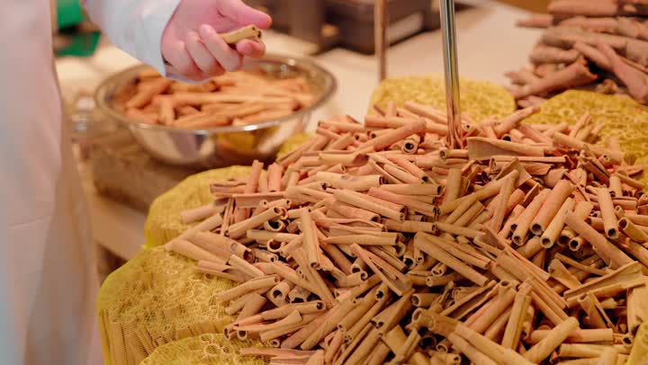 تصوير مقرب لرجل عربي خليجي اماراتي يرتدي الزي التقليدي يقف داخل متجر توابل يقوم بشم رائحة الأعشاب للتأكد من جودتها،مفهوم التسوق الواعي، المنتجات الطبيعية والعضوية، نمط حياة صحي، أسواق ومحلات المواد الغذائية