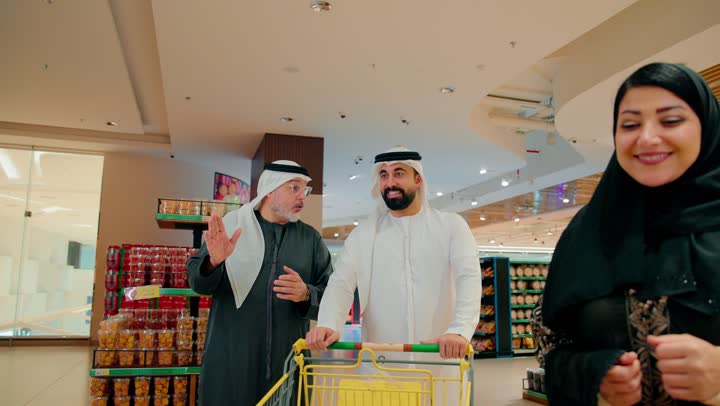 عرض المنتجات والمواد الغذائيه على الارفف في السوبرماركت، الاستفاده من التخفيضات والعروض على المنتجات، أسرة عربيه خليجيه اماراتية مستمتعه بتبضع اللوازم المنزليه، ايماءات الفرح والسعاده لقضاء أوقات ممتعه برفقه العائله