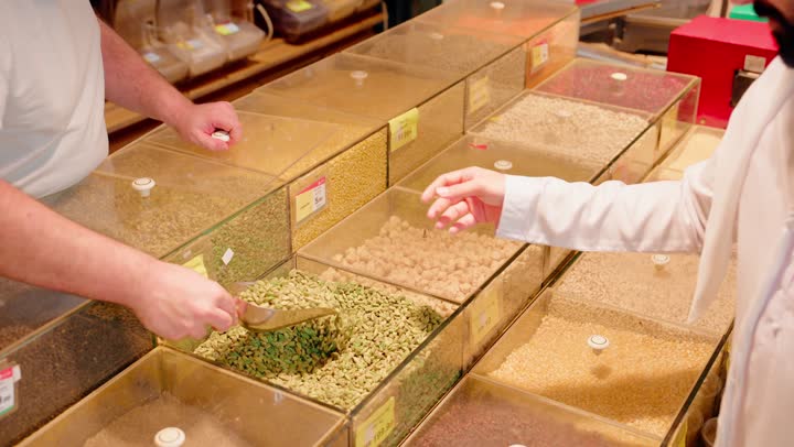 الوجبات الخفيفه والسناكات الصحيه اللذيذه، تصوير مقرب لرجل عربي خليجي اماراتي يرتدي الكندورة و الغتره يقوم بشراء المكسرات من السوبرماركت، الاستفاده من التخفيضات والعروضات على المنتجات في الامارات العربية