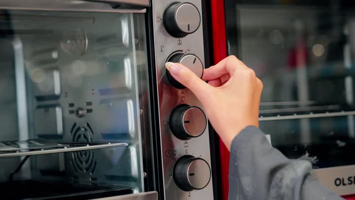 تصوير مقرب ليد امراه عربيه خليجيه اماراتية يقوم بتفقد فرن كهربائي، مفهوم الشراء الواعي، مقارنة الأجهزة المنزلية،  فحص التفاصيل قبل اتخاذ قرار الشراء، التسوق داخل متجر إلكترونيات، اختيار الفرن المناسب