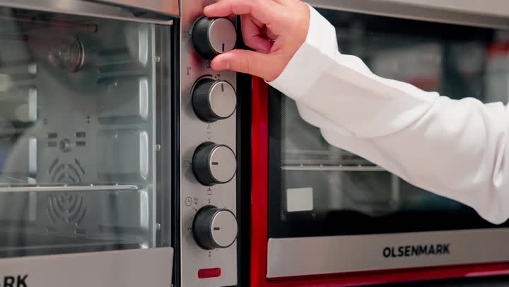 مفهوم الشراء الواعي، مقارنة الأجهزة المنزلية،  فحص التفاصيل قبل اتخاذ قرار الشراء، التسوق داخل متجر إلكترونيات، تصوير مقرب ليد رجل عربي خليجي يرتدي الزي التقليدي يقوم بتفقد فرن كهربائي، اختيار الفرن المناسب