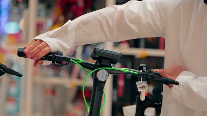 انتقاء المعدات الرياضية بعناية، أنشطة ترفيهية شبابية، تصوير مقرب لرجل عربي خليجي اماراتي يقوم بتفقد دراجات هوائية معروضة داخل المتجر، ممارسة الهوايات الرياضية الحديثة، الاهتمام بنمط الحياة الصحي