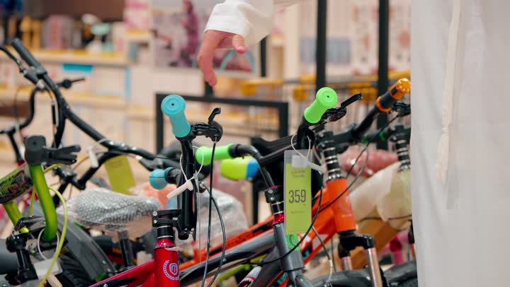 الاهتمام بنمط الحياة الصحي، ممارسة الهوايات الرياضية الحديثة، رجل عربي خليجي اماراتي  يرتدي الكندورة و الغترة يقوم بتفقد دراجات هوائية معروضة داخل المتجر، أنشطة ترفيهية شبابية، اختيار المعدات الرياضية المناسبة