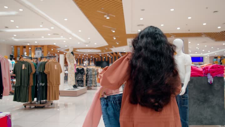 الاهتمام بالأطفال أثناء التسوق العائلي، أم عربية خليجيه اماراتية محجبة ترتدي العباءة تحتضن ابنتها داخل متجر ملابس، مشاعر الحب والترابط الأسري أثناء التسوق، تجربة تسوق عائلية مليئة بالمودة، اختيار ملابس الأطفال داخل محل ملابس