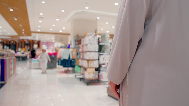 مشاعر الأمومة والاحتواء، التواصل العاطفي بين أفراد الأسرة، أم عربية خليجيه محجبة تحتضن ابنها داخل مركز تسوق، الحب والحنان أثناء التسوق العائلي، مفهوم العلاقة الأسرية الدافئة بين الأم والطفل