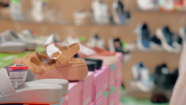 Comparing different designs, a close-up shot of the hand of a Gulf Arab woman choosing women's shoes inside a shoe store, focusing on women's elegance and comfort, the variety of women's shoe designs on display.