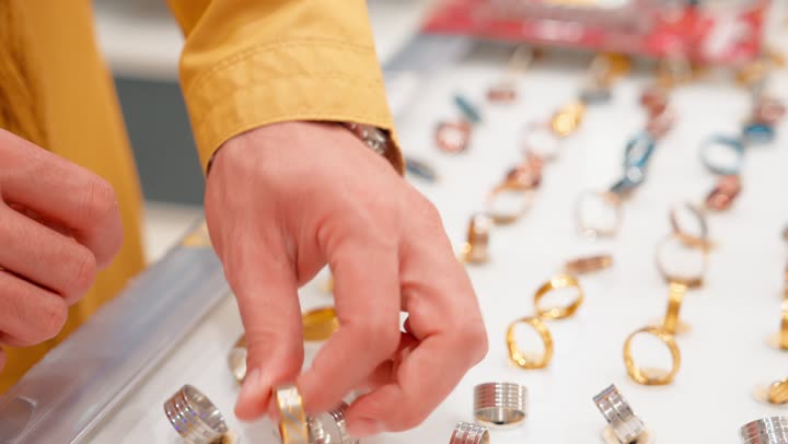 مفهوم اختيار المجوهرات بعناية واهتمام، تصوير مقرب لرجل عربي خليجي اماراتي يقوم بتجربة خاتم ذهبي داخل المتجر، التأكد من المقاس المناسب، الاهتمام بالتفاصيل والأناقة الشخصية