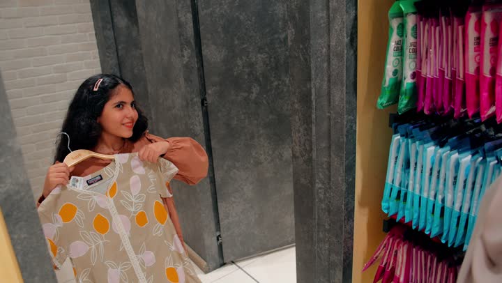 إبراز الأناقة الطفولية والاهتمام بالمظهر، تجربة تسوق ممتعة للأطفال، بنت عربية خليجية امارتية تقوم بتجربة بلوزة داخل متجر ملابس برفقة والدتها، التسوق العائلي داخل المتاجر التجارية
