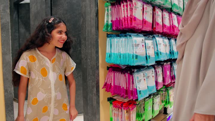 بنت عربية خليجية امارتية تقوم بتجربة بلوزة داخل متجر ملابس برفقة والدتها، التسوق العائلي داخل المتاجر التجارية، الأناقة الطفولية والاهتمام بالمظهر، تجربة تسوق ممتعة للأطفال