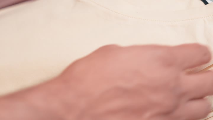 مفهوم التسوق الواعي والانتباه للتفاصيل، اختيار دقيق للمنتجات قبل الشراء، التسوق داخل متجر ملابس، تصوير مقرب ليد شاب عربي خليجي اماراتي يقوم بتفقد جودة الأقمشة ومقاسات الملابس الجاهزة، تجربة شراء داخل متجر أزياء رجالي