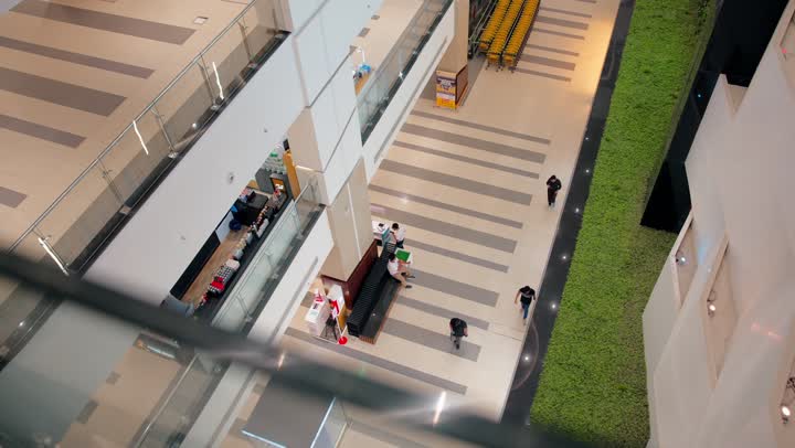 تصوير علوي لمركز تسوق حديث، أشخاص يتنقلون بين الطوابق والممرات الواسعة، مفهوم التسوق والترفيه داخل مولات الامارات العربية