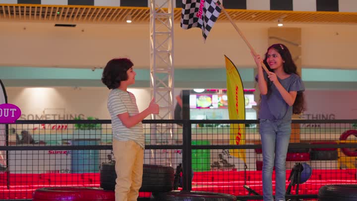 مفهوم التحدي والنجاح، بنت عربية خليجيه اماراتية ترتدي الزي الكاجوال تلوح بعلم سباق السيارات تعبيرًا عن الفوز برفقة اخيها ، ايماءات السعادة و السرور