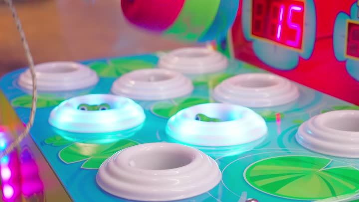 تصوير مقرب ليد ولد عربي خليجي اماراتي يلعب لعبة اضرب الخلد داخل صالة ألعاب إلكترونية، استخدام مطرقة مطاطية لضرب الدمى المضيئة المتحركة، أجواء ترفيهية ممتعة، الاستمتاع بالألعاب الحركية التفاعلية داخل المراكز الترفيهية