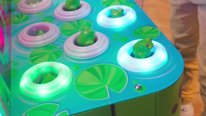 استخدام مطرقة مطاطية لضرب الدمى المضيئة المتحركة، تصوير مقرب ليد ولد عربي خليجي اماراتي يلعب لعبة اضرب الخلد داخل صالة ألعاب إلكترونية، أجواء ترفيهية ممتعة، الاستمتاع بالألعاب الحركية التفاعلية داخل المراكز الترفيهية