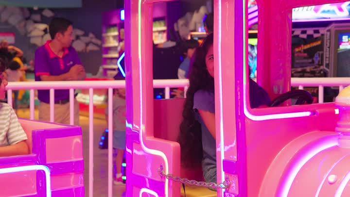 أجواء ترفيهية داخل صالة ألعاب، طفلان عربيان خليجيان اماراتيان يرتديان الزي الكاجوال يستمتعان بركوب لعبة القطار الترفيهي، أنشطة ترفيهية مخصصة للأطفال، ايماءات السعادة والسرور