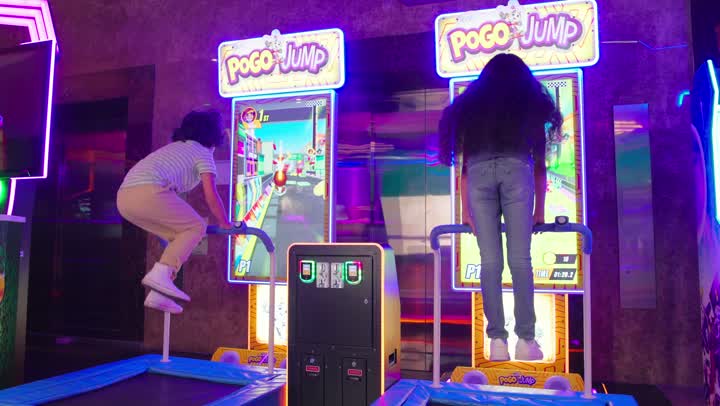 مفهوم الترفيه والتسلية، طفلان عربيان خليجيان اماراتيان يرتيدان الزي الكاجوال يمارسان لعبة القفز الإلكترونية داخل مركز ألعاب حديث، أنشطة حركية وأجواء ترفيهية