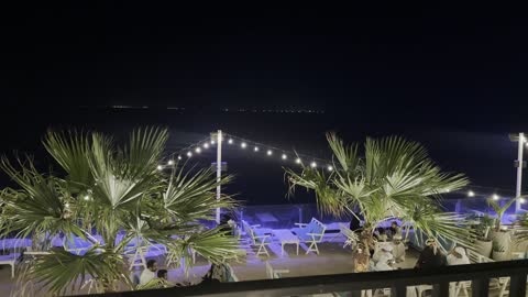 An artificial palm tree with green leaves, the Jubail Corniche, famous tourist attractions, the tourist waterfront in the Kingdom of Saudi Arabia in the city of Jubail Industrial, a collection of restaurants and cafes overlooking the sea.