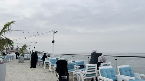 An outdoor seating area overlooking the sea with a recreational atmosphere, a collection of restaurants and cafes facing the sea, the tourist waterfront in the Kingdom of Saudi Arabia in the city of Jubail Industrial, Jubail Corniche, famous tourist attractions.