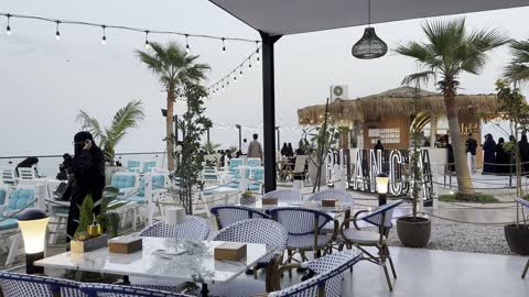 The feeling of relaxation due to the presence of palm trees and plants in the area, the tourist waterfront in the Kingdom of Saudi Arabia in the city of Jubail Industrial on December 28, 2025, a collection of restaurants and cafes overlooking the sea, Jubail Corniche, famous tourist attractions.