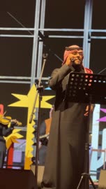 The singer and musicians wear traditional Saudi attire, a traditional band on a well-lit stage, the Ithra Food Festival from December 22 to January 1, 2026, at the King Abdulaziz Center for World Culture (Ithra) in Dhahran, Saudi Arabia, with a unique design resembling pebbles.