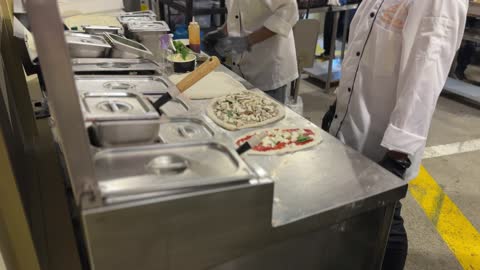 اعداد وطهي الفطائر والبيتزا في مهرجان إثراء للطعام من ٢٢ ديسمبر حتى ع يناير ٢٠٢٦، مركز الملك عبد العزيز للثقافة العالمية (إثراء) في الظهران في المملكة العربية السعودية، تصميم فريد يشبه الحصى، يضم مرافق ثقافية وتعليمية متنوعة مثل مكتبة ومتحف ومسرح وسينما