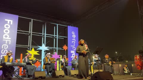عازف كمان على المسرح وعازف على آلة وترية، فرقة موسيقية تقليدية على خشبة مسرح مضاءة، مهرجان إثراء للطعام من ٢٢ ديسمبر حتى ع يناير ٢٠٢٦، مركز الملك عبد العزيز للثقافة العالمية (إثراء) في الظهران في المملكة العربية السعودية، تصميم فريد يشبه الحصى