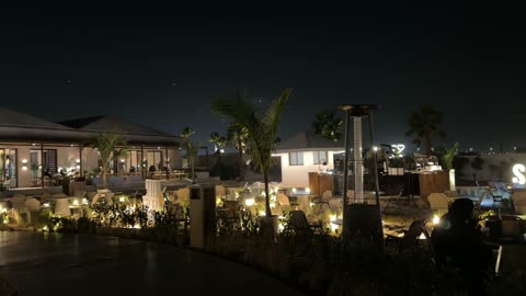 The use of heaters in outdoor seating, the sea breeze at the Corniche of Khobar in the Eastern Province, Kingdom of Saudi Arabia, entertainment events and activities, tourist restaurants and cafes, a family-friendly coastal beach destination, a calm atmosphere, and an enjoyable relaxation experience.