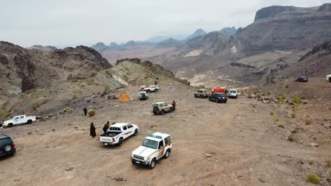 The volcanic fields in Tabuk are laboratories for ancient volcanic activity in the Kingdom of Saudi Arabia, trade caravan routes, an important tourist and geological site with archaeological inscriptions and rock formations, dormant volcanic fields with rugged terrain, and four-wheel-drive vehicles in a desert area.