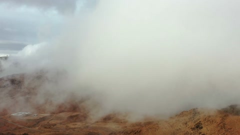 A white cloud over dormant volcanic fields with rugged terrain, the volcanic fields in Tabuk are laboratories for ancient volcanic activity in the Kingdom of Saudi Arabia, trade caravan routes, an important tourist and geological site with archaeological inscriptions and rock formations.