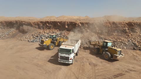 A large-scale mining operation in a desert area, a cement factory or quarry in Saudi Arabia, mixing concrete components, cement paste for construction and building, construction sites, concrete barriers to separate stored materials.