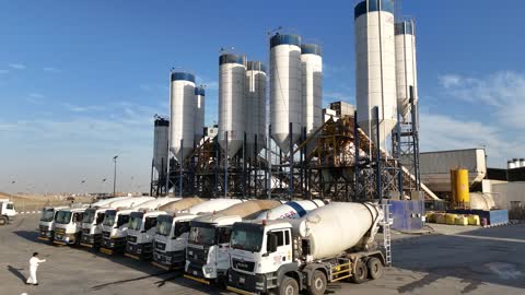 شاحنات خلط الخرسانة في مصنع أسمنت أو محجر في المملكة العربية السعودية، خلط مكونات الخرسانة ، عجينة اسمنتية للبناء والانشاء ، اماكن انشائية، حواجز خرسانية لفصل المواد المخزنة