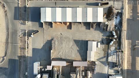 مصنع أسمنت أو محجر في المملكة العربية السعودية، خلط مكونات الخرسانة ، عجينة اسمنتية للبناء والانشاء ، اماكن انشائية، أكوام كبيرة من المواد الخام الحصى، الرمل أو الركام مخزنة تحت هياكل، حواجز خرسانية لفصل المواد المخزنة