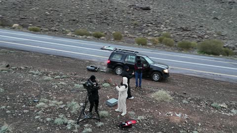 أشخاص يرتدون ملابس شتوية ومركبات للطرق الوعرة، سلسلة جبال الحرة في منطقة تبوك تكسوها الثلوج، أجواء ثلجية باردة، جبال منحوتة وتشكيلات جبلية في مدينة تبوك، معالم حضارية سياحية في المملكة العربية السعودية، تصوير درون جوي للتكوينات الصخرية