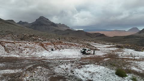 Cold snowy atmosphere, the Al-Harra mountain range in the Tabuk region is covered in snow, sculpted mountains and geological formations in the city of Tabuk, cultural and tourist landmarks in the Kingdom of Saudi Arabia, aerial drone photography of rock formations.