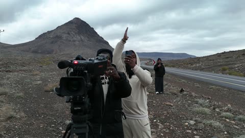 People wearing winter clothes and off-road vehicles, the Al-Harra mountain range in the Tabuk region covered in snow, cold snowy atmosphere, sculpted mountains and rock formations in the city of Tabuk, cultural and tourist landmarks in the Kingdom of Saudi Arabia, aerial drone photography of rock formations.
