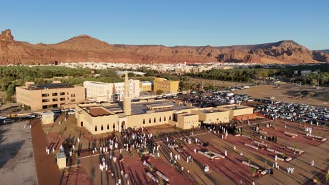 A place for worship and getting closer to God Almighty, a drone shot of an Islamic mosque in Al-Ula Governorate in the Kingdom of Saudi Arabia, trees and green plants, mountains and rock formations, a famous tourist area.