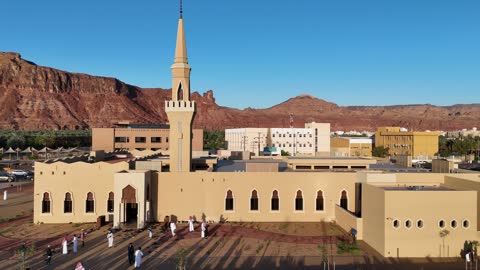 The mountains and rock formations, a place for worship and getting closer to God Almighty, a drone shot of an Islamic mosque in Al-Ula Governorate in the Kingdom of Saudi Arabia, trees and green plants, a famous tourist area.