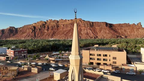 The mountains and rock formations, a place for worship and getting closer to God Almighty, a drone shot of an Islamic mosque in Al-Ula Governorate in the Kingdom of Saudi Arabia, trees and green plants, a famous tourist area.