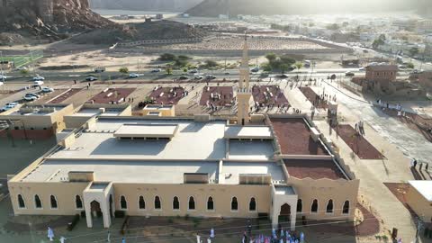 A place for worship and getting closer to God Almighty, a drone shot of an Islamic mosque in Al-Ula Governorate in the Kingdom of Saudi Arabia, trees and green plants, mountains and rock formations, a famous tourist area.