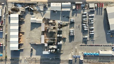 مصنع متخصص في أعمال الخرسانة الجاهزة والأساسات الميكانيكية ، خلط مكونات الخرسانة ، عجينة اسمنتية للبناء والانشاء ، اماكن انشائية، أكوام كبيرة من المواد الخام الحصى، الرمل أو الركام مخزنة تحت هياكل، حواجز خرسانية لفصل المواد المخزنة