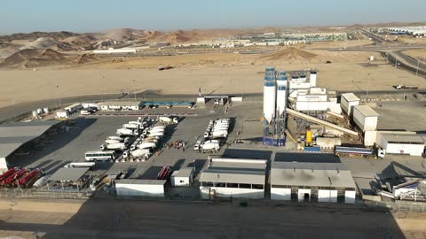 مصنع للخرسانة الجاهزة، خلط مكونات الخرسانة ، عجينة اسمنتية للبناء والانشاء ، اماكن انشائية، أكوام كبيرة من المواد الخام الحصى، الرمل أو الركام مخزنة تحت هياكل، حواجز خرسانية لفصل المواد المخزنة