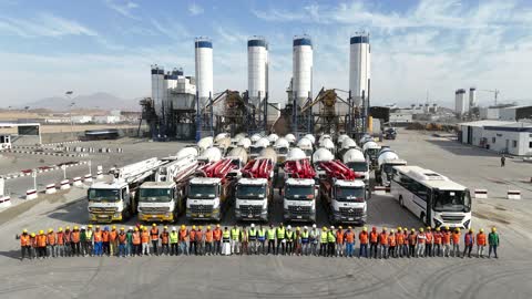 Workers wear hard hats and reflective vests, vehicles for transporting ready-mixed concrete from the factory to construction sites, production of concrete for construction and civil engineering projects, a factory specialized in ready-mixed concrete and mechanical foundations, mixing concrete components, cement paste for construction and building.
