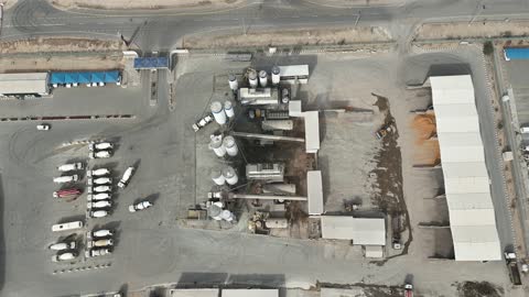 شاحنات ومعدات ثقيلة في المكان، الخزانات الكبيرة في جزء من المحطة، إنتاج الخرسانة لمشاريع البناء والهندسة المدنية ، مصنع متخصص في أعمال الخرسانة الجاهزة والأساسات الميكانيكية ، خلط مكونات الخرسانة ، عجينة اسمنتية للبناء والانشاء