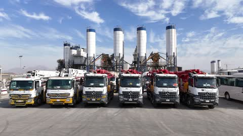 Concrete mixing trucks parked in the factory yard, producing concrete for construction and civil engineering projects, a factory specialized in ready-mixed concrete and mechanical foundations, mixing concrete components, cement paste for construction and building, large piles of raw material gravel.