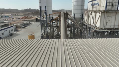 شاحنات ومعدات ثقيلة في المكان، الخزانات الكبيرة في جزء من المحطة، إنتاج الخرسانة لمشاريع البناء والهندسة المدنية ، مصنع متخصص في أعمال الخرسانة الجاهزة والأساسات الميكانيكية ، خلط مكونات الخرسانة ، عجينة اسمنتية للبناء والانشاء