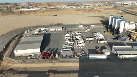 مصنع للخرسانة الجاهزة، خلط مكونات الخرسانة ، عجينة اسمنتية للبناء والانشاء ، اماكن انشائية، أكوام كبيرة من المواد الخام الحصى، الرمل أو الركام مخزنة تحت هياكل، حواجز خرسانية لفصل المواد المخزنة