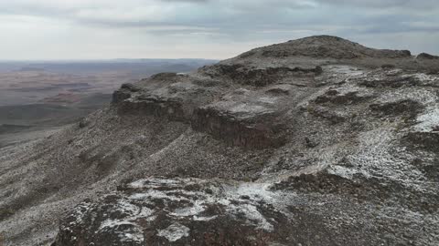 Light accumulation of snow on the peaks and rocky elevations, cultural and tourist landmarks in the Kingdom of Saudi Arabia, cold snowy atmosphere, the Al-Harra mountain range in the Tabuk region covered in snow, sculpted mountains and geological formations, aerial drone photography of the rock formations.