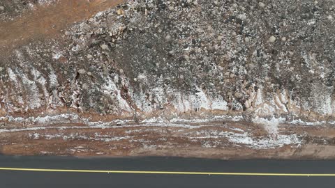 Snow accumulates on rocks and trees, tourist cultural landmarks in the Kingdom of Saudi Arabia, cold snowy atmosphere, the Al-Harra mountain range in the Tabuk region is covered in snow, sculpted mountains and geological formations, aerial drone photography of rock formations.